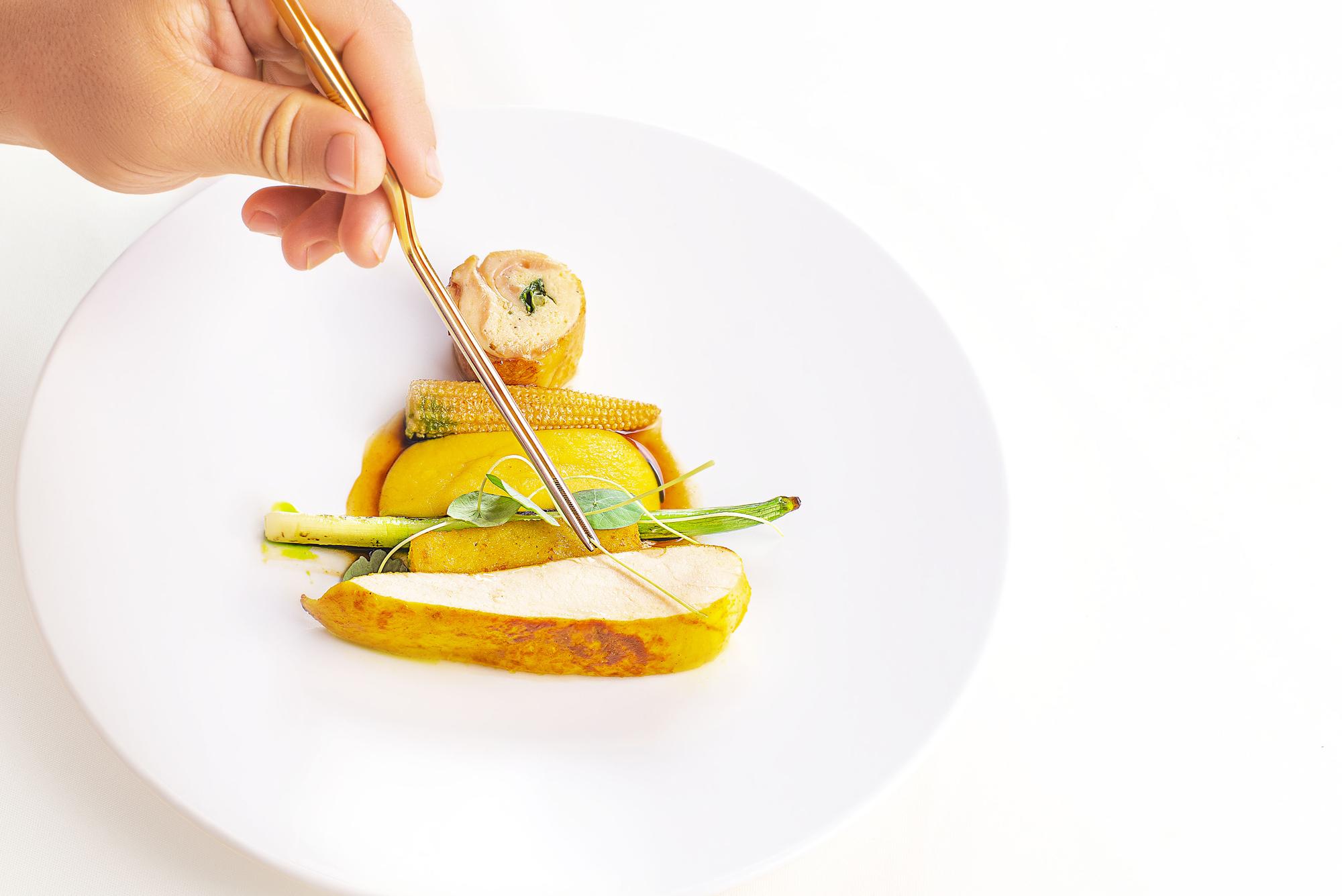 Chef plating a colorful dish on a wooden table